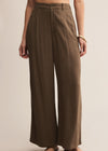 Brown wide-leg pants worn by a person on a beige background