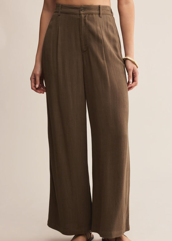 Brown wide-leg pants worn by a person on a beige background