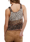 Woman wearing a patterned tank top and brown pants on a white background