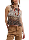 Woman wearing a patterned sleeveless top and brown pants on a white background