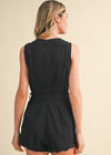 Woman wearing a black romper with scalloped edges on a beige background