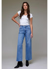 Woman wearing a white t-shirt and blue jeans against a neutral background