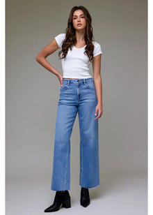  Woman wearing a white t-shirt and blue jeans against a neutral background