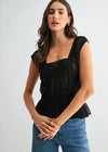 Woman wearing a black top and blue jeans against a white background