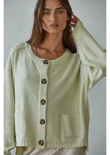  Woman wearing a light green cardigan with buttons against a plain background