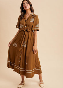  Woman wearing a brown dress with white embroidery on a beige background