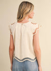 Woman wearing a beige top with lace details on a beige background