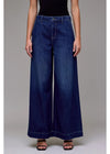 Person wearing wide-leg blue jeans on a plain background