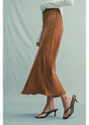 Brown polka dot skirt worn by a person on a light green background