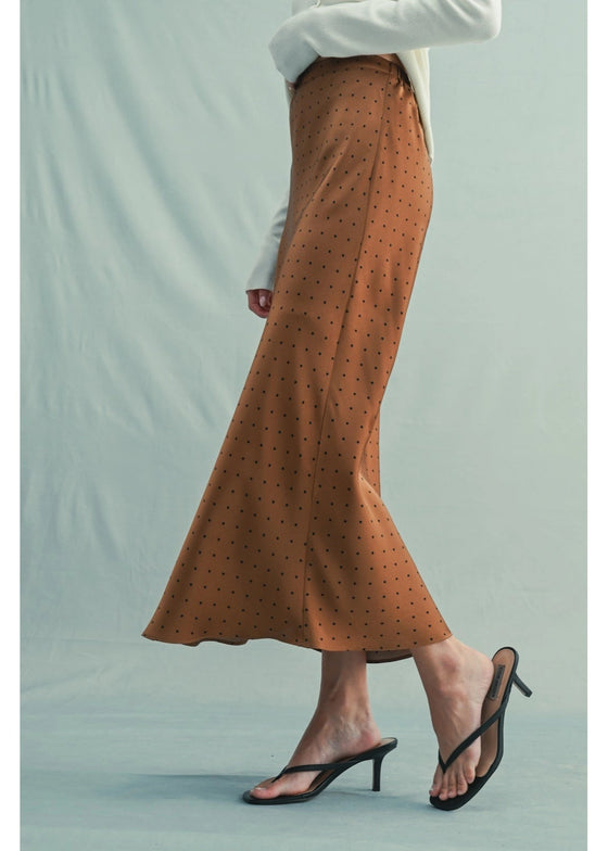 Brown polka dot skirt worn by a person on a light green background