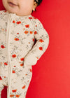 Child wearing a floral onesie against a red background