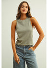 Woman wearing a green tank top and blue jeans against a plain background