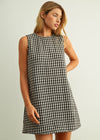Woman wearing a black and white checkered dress against a plain background