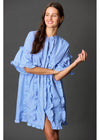 Woman wearing a blue dress with ruffled details on a gray background