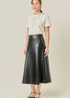Woman wearing a white top and black leather skirt on a beige background