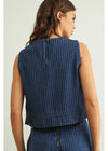 Woman wearing a blue denim vest against a plain background