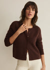 Woman wearing a brown cardigan against a plain background