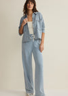 Woman wearing a light blue denim outfit on a plain background
