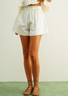 Person wearing white shorts and brown sandals on a plain background