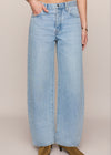 Person wearing light blue wide-leg jeans on a beige background