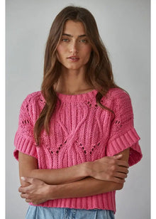  Woman wearing a pink knitted sweater against a gray background