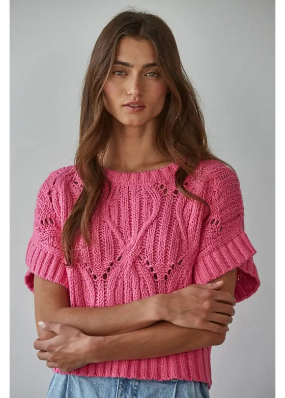 Woman wearing a pink knitted sweater against a gray background