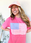 Woman wearing a pink t-shirt with an American flag design and a matching pink cap.