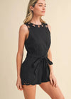 Woman wearing a black romper with cut-out details on a beige background
