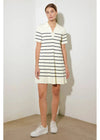 Woman wearing a striped dress with white sneakers against a plain background
