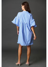 Woman wearing a light blue dress with ruffled sleeves on a dark gray background