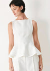 Woman wearing a white sleeveless top with a plain background