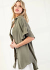 Woman wearing an olive green button-up shirt over a white top on a white background