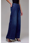 Person wearing wide-leg blue jeans on a plain background