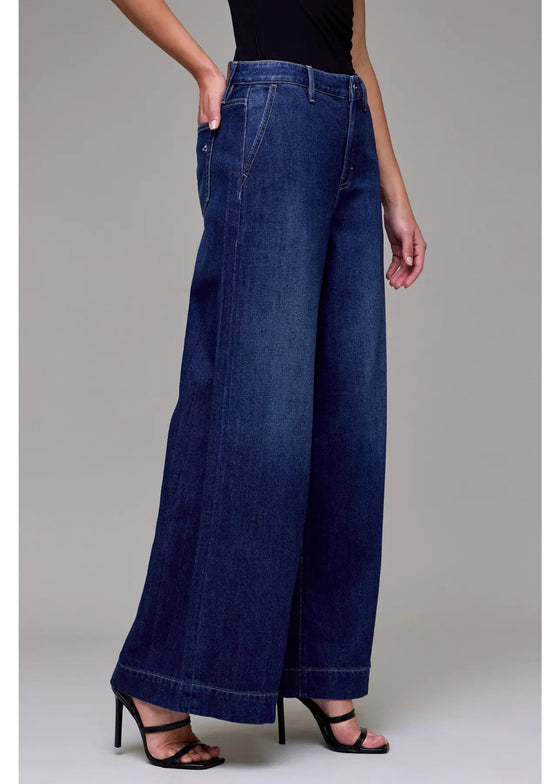 Person wearing wide-leg blue jeans on a plain background