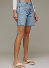 Person wearing light blue denim shorts on a neutral background