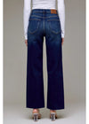 Person wearing blue wide-leg jeans with a plain background