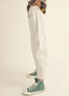 Person wearing white pants and green high-top sneakers on a beige background