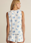 Woman wearing a sleeveless top and shorts with blue floral patterns on a beige background