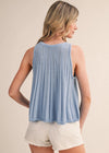 Woman wearing a light blue sleeveless top and white shorts on a beige background