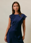 Woman wearing a navy blue dress with lace sleeves against a neutral background