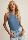 Woman wearing a blue tank top and denim shorts on a beige background