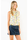 Woman wearing a sleeveless floral top and denim skirt on a white background