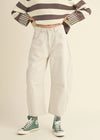 Person wearing a striped sweater, white jeans, and green high-top sneakers on a beige background