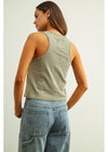 Woman wearing a green tank top and blue jeans on a plain background