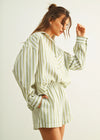 Woman wearing a green and white striped outfit against a plain background