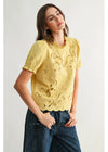 Woman wearing a yellow lace top and blue jeans on a white background