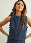 Woman wearing a blue pinstripe sleeveless top against a plain background