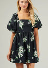 Woman wearing a black floral dress against a gray background