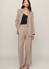 Woman wearing a beige pinstripe suit on a plain background
