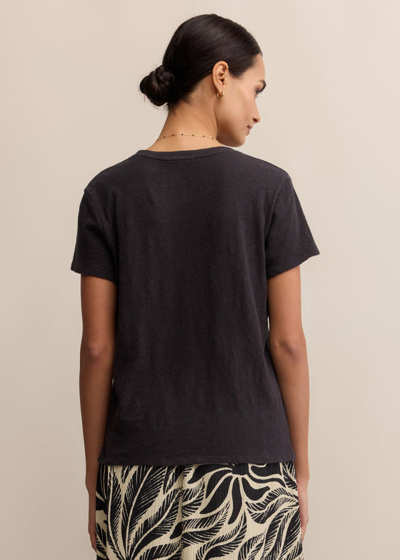 Woman wearing a black t-shirt and patterned pants on a beige background